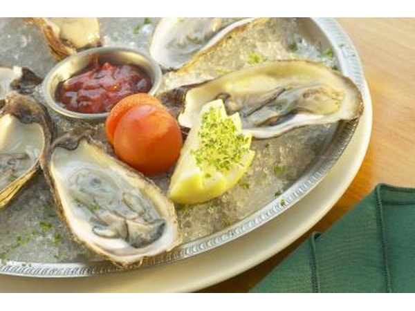 A raw oyster platter with dipping sauce and garnishes.