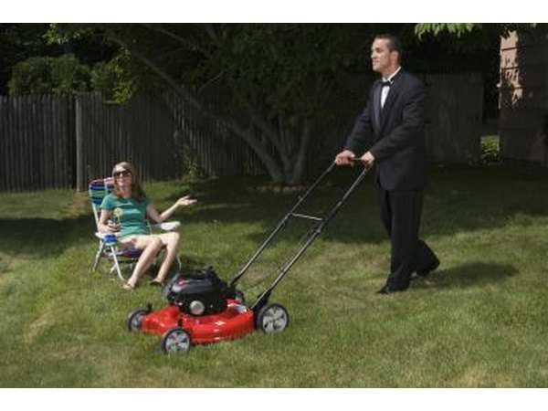 Man in suit mowing lawn slowly.