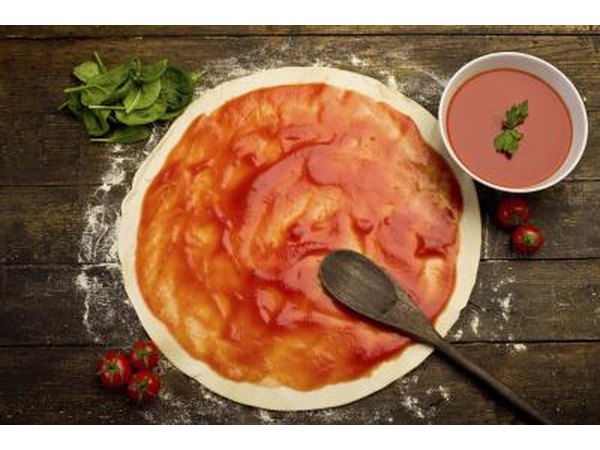 Tomato sauce being spread onto some pizza dough.