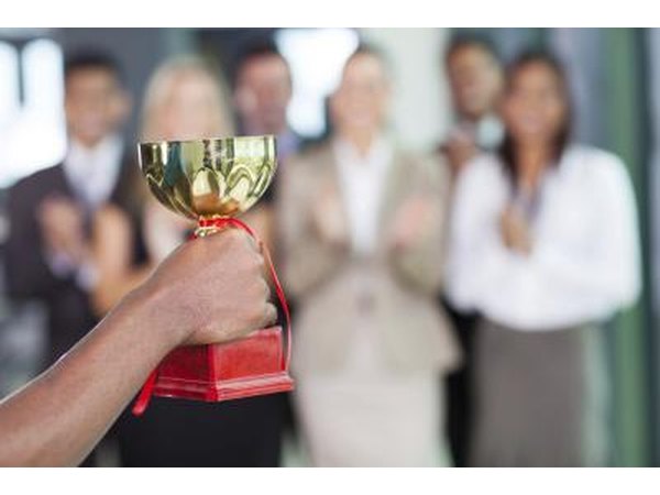 Hand holding up trophy in front of business employees
