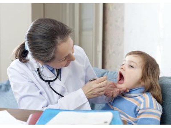 A pediatrician examines a child's throat.