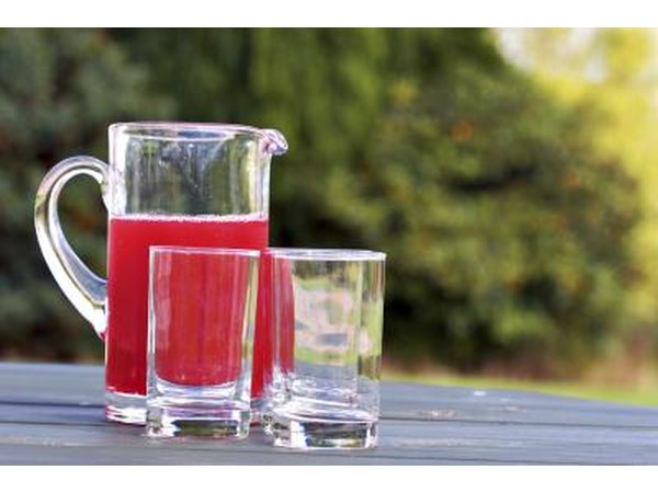 Pitcher of cranberry juice and drinking glasses on a wooden table