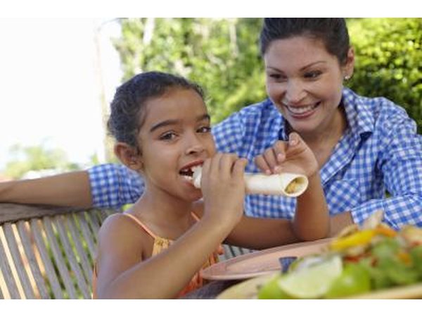 A girl eats a soft flour tortilla with her favorite filling.