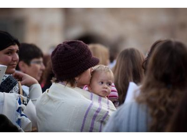 Woman wearing a shawl holds her baby at the Wailing Wall