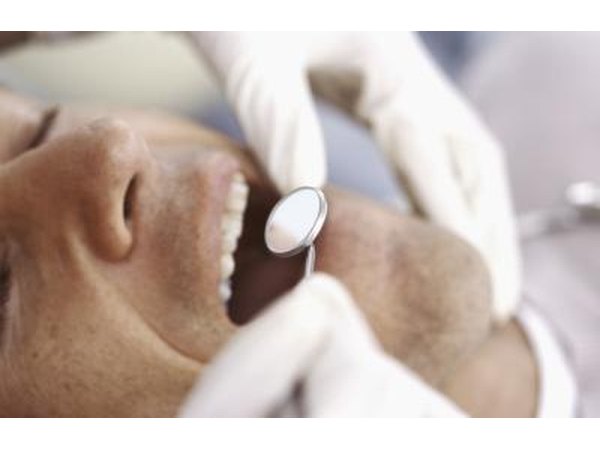 A doctor inspects a patient's tongue with a mirror.