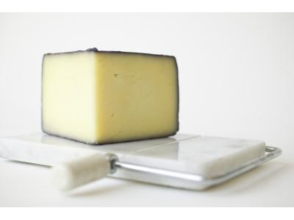 A wedge of cheese on a cutting board.