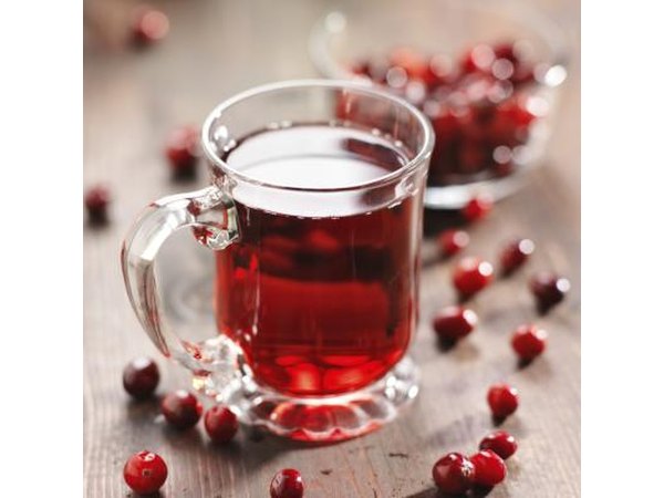 A glass cup of cranberry juice and cranberries on a wooden table