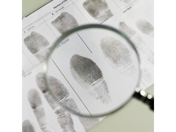 A magnifying glass over a fingerprint on paper.