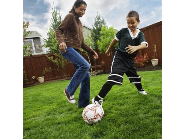 Mother and son playing soccer in backyard