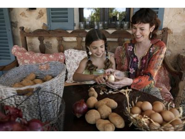A mother and daughter peeling potatoes.