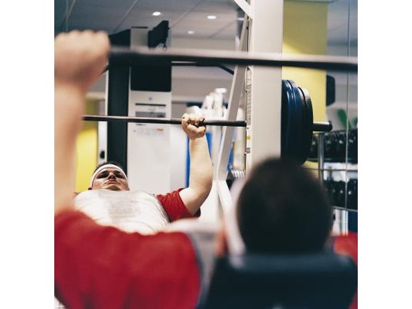 An overweight endomorphic man lifts weight at the gym.