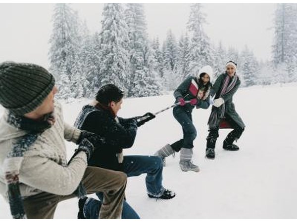 Friends playing a game of tug-of-war in the snow.