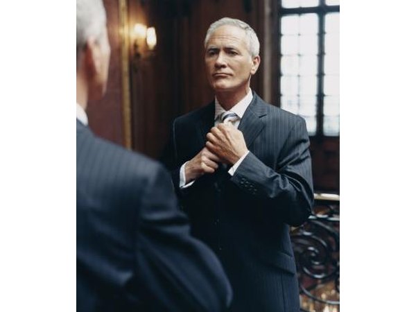 Executive adjusting tie and looking in mirror