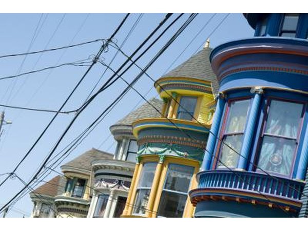 Cable car lines run by a blue Victorian with mauve trim around the windows.