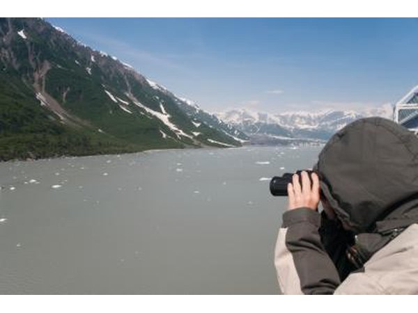 A man examines the Alaskan landscape through binoculars.