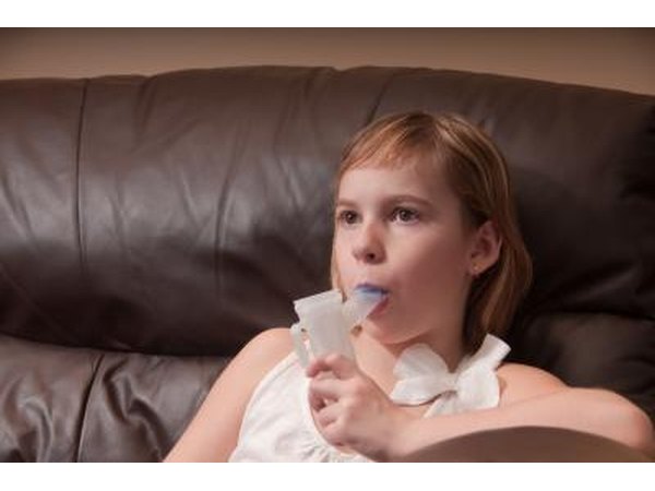 Young girl on sofa breathing mist from a nebulizer