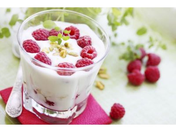 A small glass filled with yogurt and fresh raspberries.