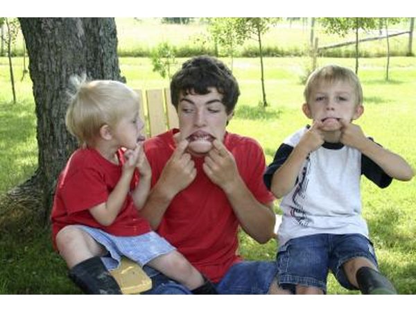 An older brother plays with his young siblings outside.