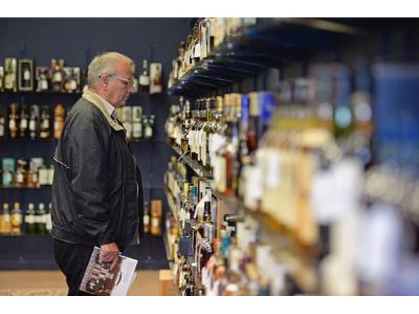 Man admires bottles of whiskey at auction