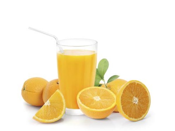 Cup of orange juice surrounded by fresh oranges.