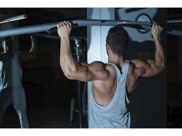 A young man is doing chin ups for his back and arm muscles.