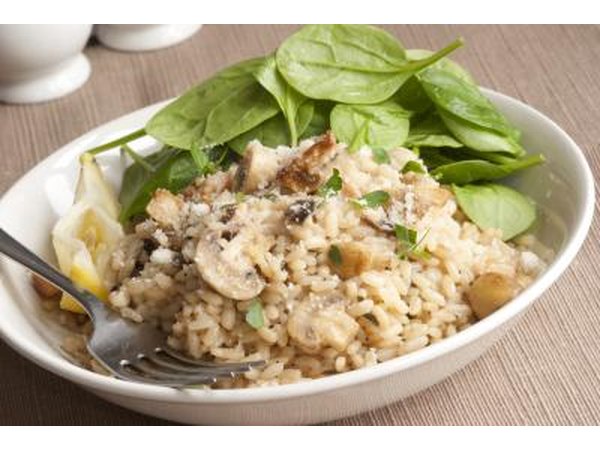 A bowl of brown rice risotta served with fresh baby spinach.