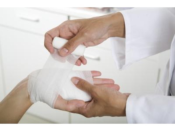 A doctor applies a bandage to a patient's palm.