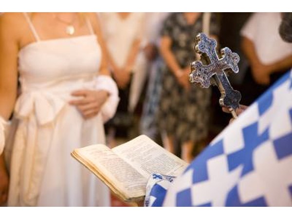 A bride standing in front of the officiate of her church wedding.