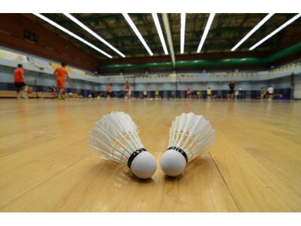 Two shuttles sit on an indoor badminton court.