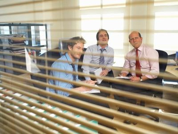 Men having meeting behind blinds.