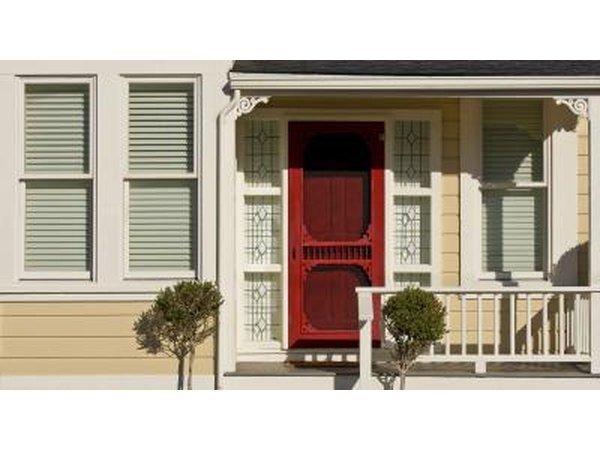 A red wooden door on a sunny porch.