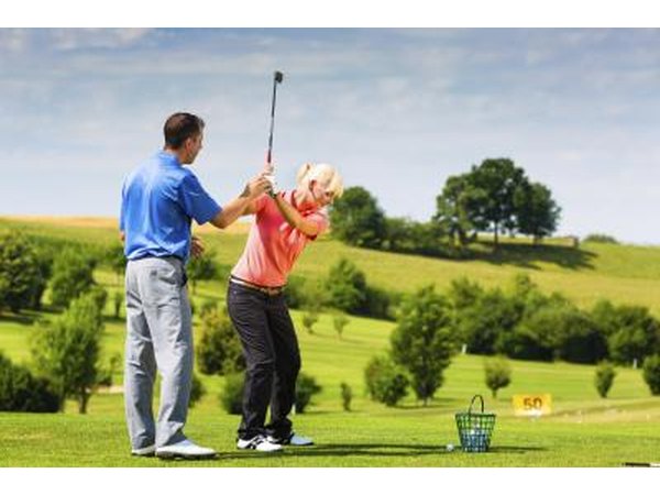 Golf instructor helping woman's swing