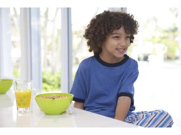 Child sitting beside bowl of cereal.