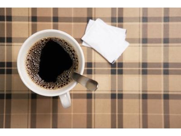 A cup of coffee with sugar packets.