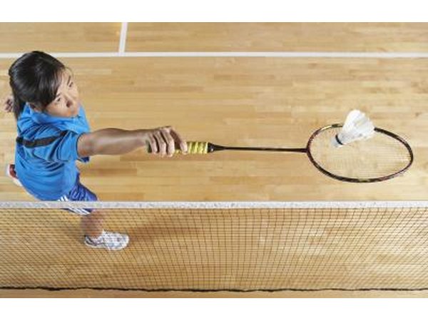 A woman uses a backhand stroke to hit the shuttle over the net.