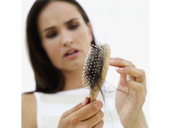 Woman looking at brush full of hair.