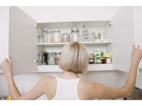 Woman opens kitchen cabinets with both hands.