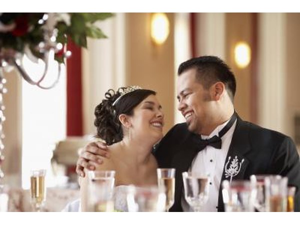 A happy bride and groom sit at a table at their wedding reception.