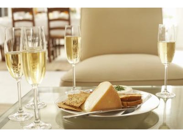 Assortment of cheeses beside glasses of white wine.
