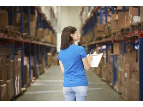 Warehousemen use inventory sheets as they count inventory in the main warehouse area.