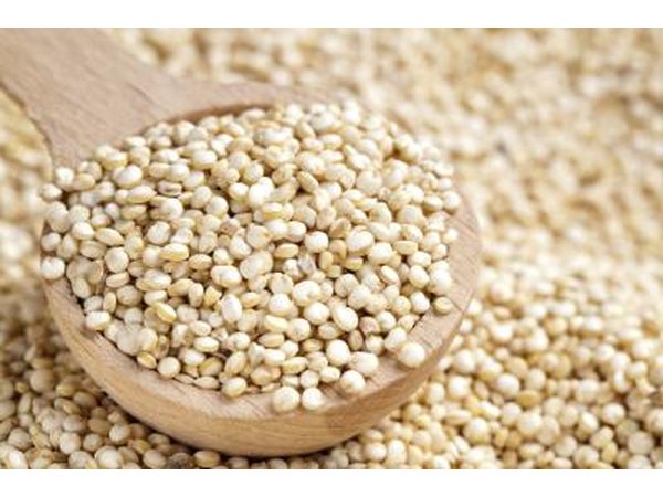 A wooden spoon filled with quinoa.
