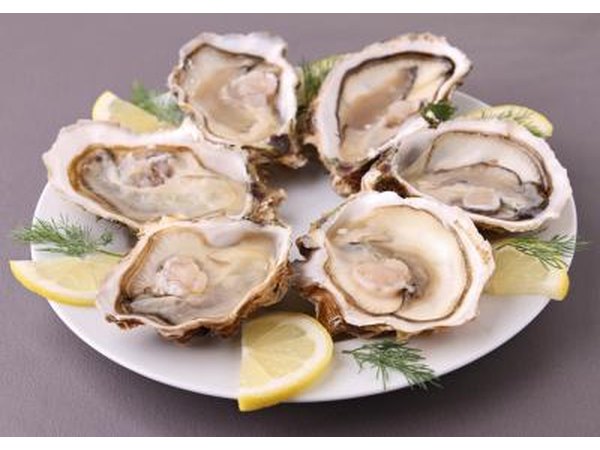 A plate of fresh oysters with lemon slices.