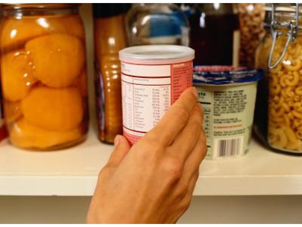 Hand reaching for canned food with nutrition label visible.