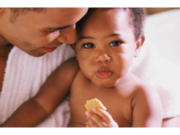 Dad cuddling a toddler eating a snack