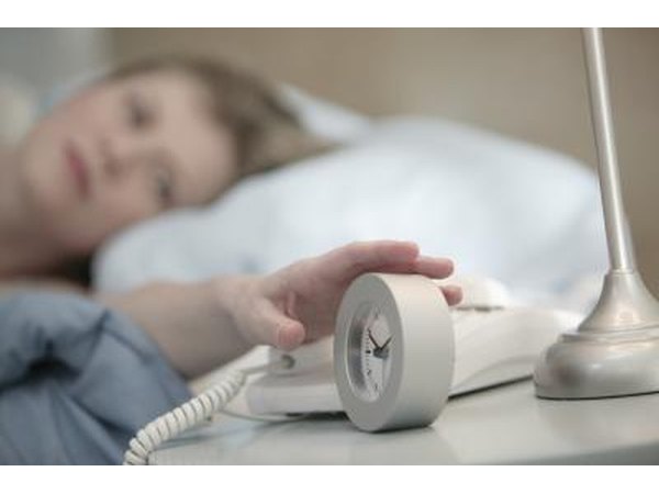 Woman reaching for an alarm clock.