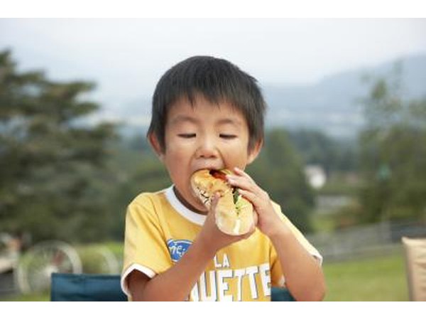 Young boy eating a hotdog.