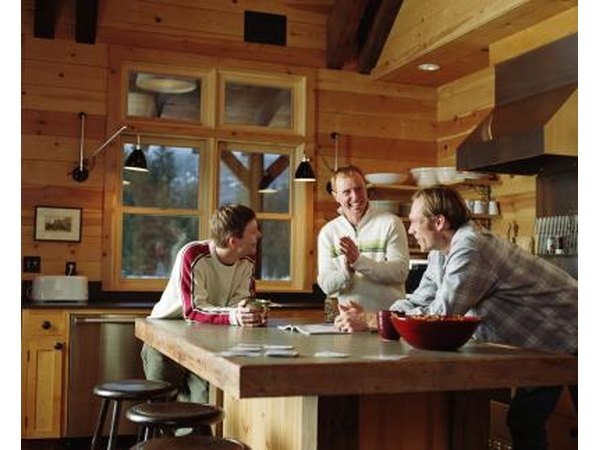 Three men talk at a kitchen island in a small kitchen.