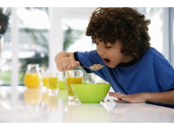 A boy eating a spoonful of breakfast cereal.