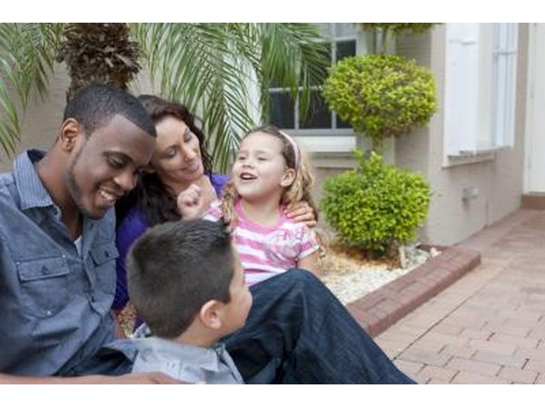 A family on a brick sidewalk in front of thier home.