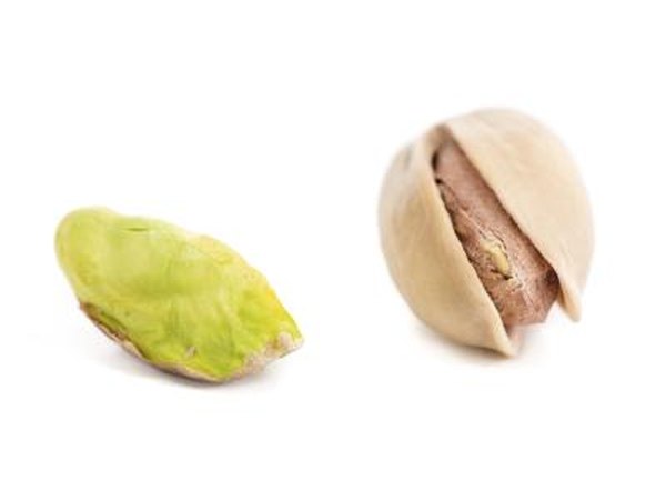 Two pistachios one shelled, and one without the shell.